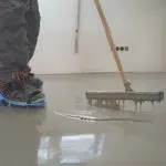 A main installing a self leveling concrete flooring in Dubai