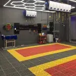 A modern garage with durable interlocking floor tiles in a structured pattern, featuring red, yellow, and gray colors.