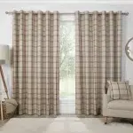 A pair of beige and red plaid curtains hanging on a window in a living room.