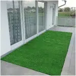 Bright green artificial turf carpet placed on a balcony or rooftop.