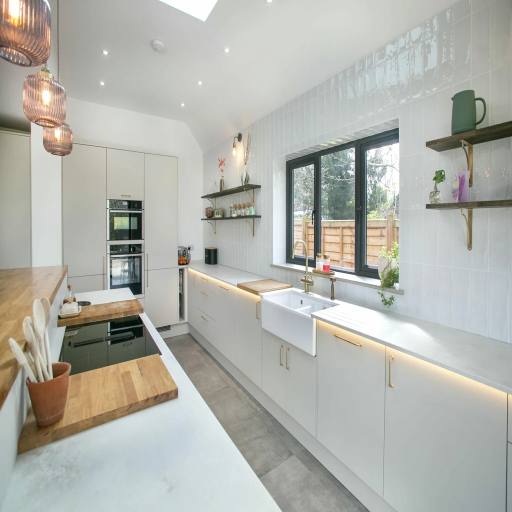 Modern white kitchen with farmhouse sink brass fixtures and wood accents