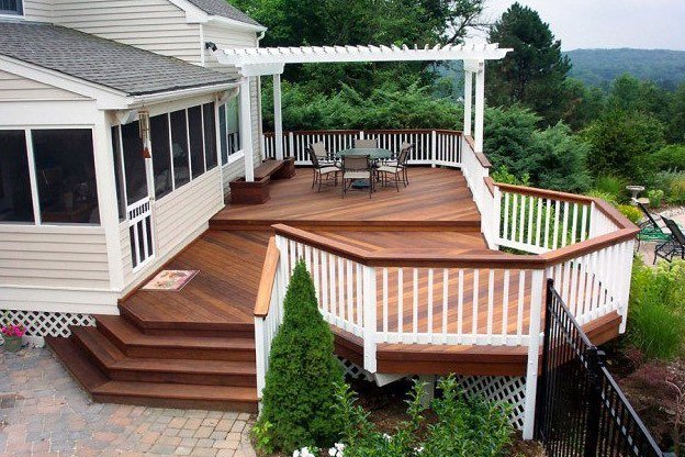 Multi level hardwood deck with white pergola and railing attached to house