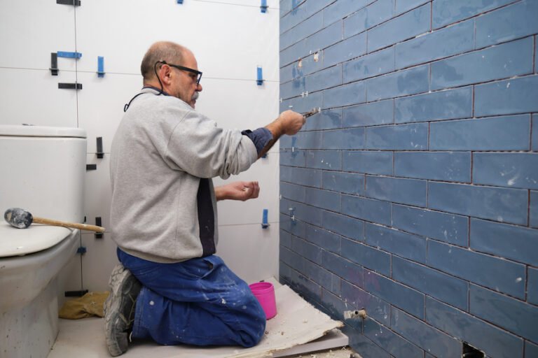 tiler-fitting-blue-metro-brick-wall-tiles-in-a-bathroom-using-tile-spacers-and-adhesive