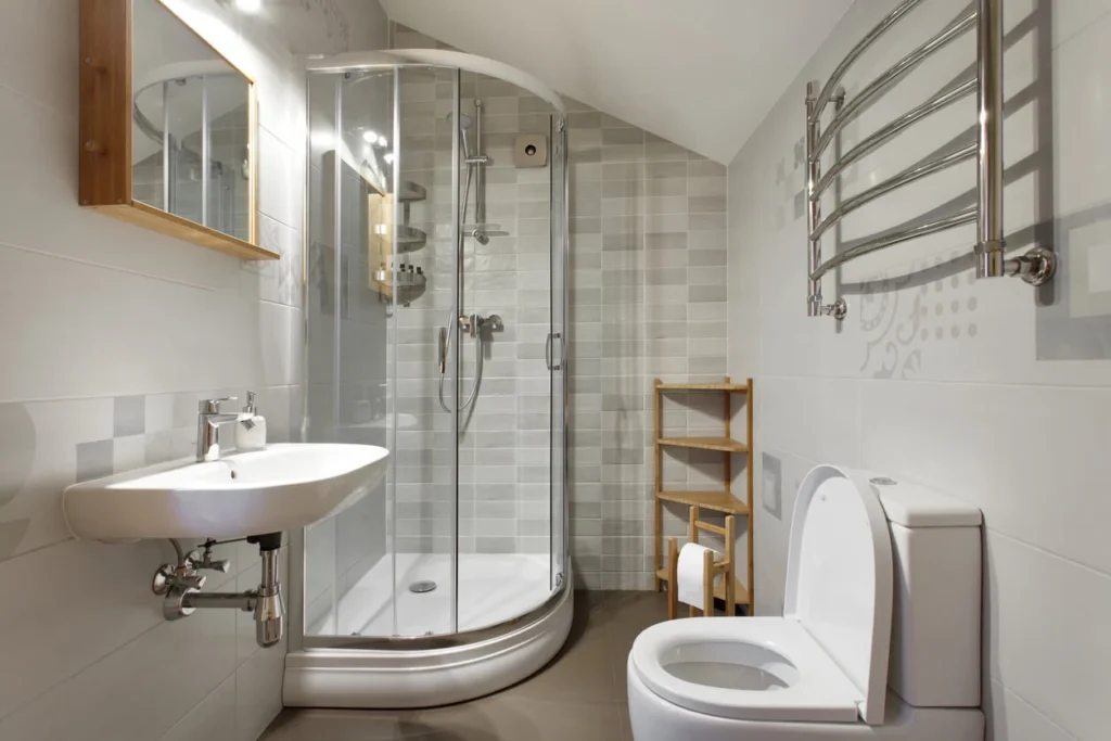 small white bathroom with quadrant corner shower enclosure wall mounted basin chrome towel rail and wooden shelving unit