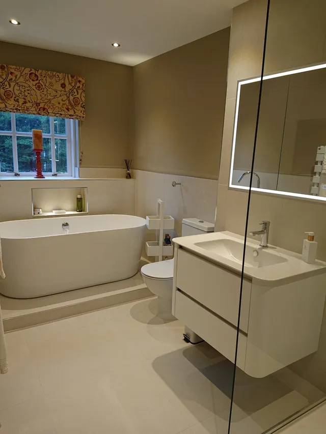 spacious neutral bathroom with freestanding oval bath floating white vanity unit led mirror cabinet and large format floor tiles