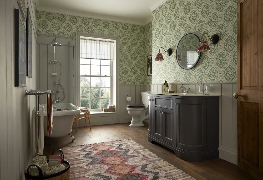 traditional country style bathroom with clawfoot roll top bath dark grey curved vanity unit botanical wallpaper and wooden flooring